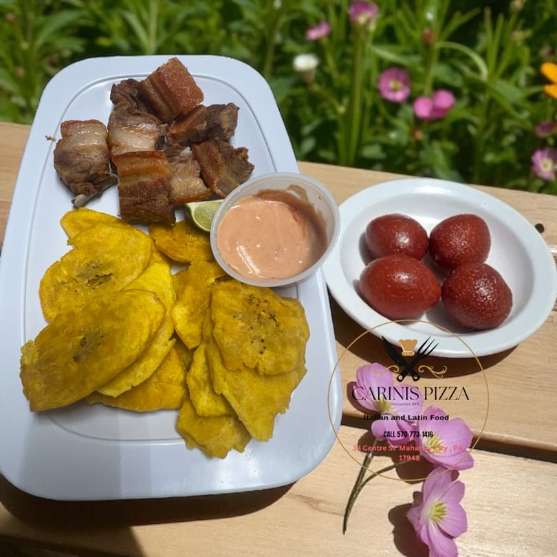 Fried pork belly, plantain chips, dipping sauce, and red fruits served outdoors at Carinis Pizza.